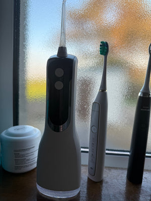 Customer photo: Hetrios Water Flosser beside two electric toothbrushes on a windowsill