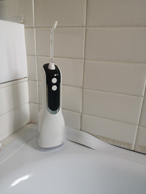 Customer photo: Hetrios Water Flosser standing in a tiled bathroom corner